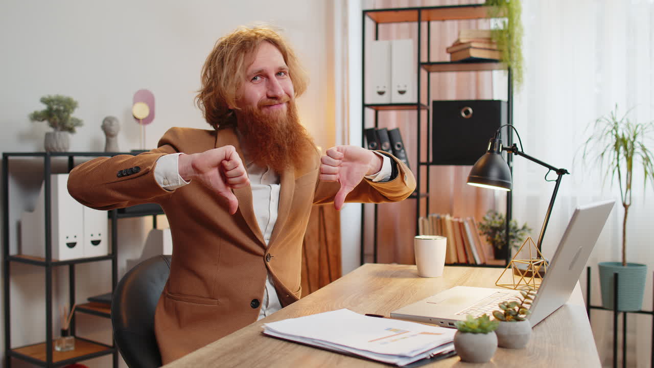 Businessman working on laptop computer at home office showing thumbs down sign gesture dissatisfied