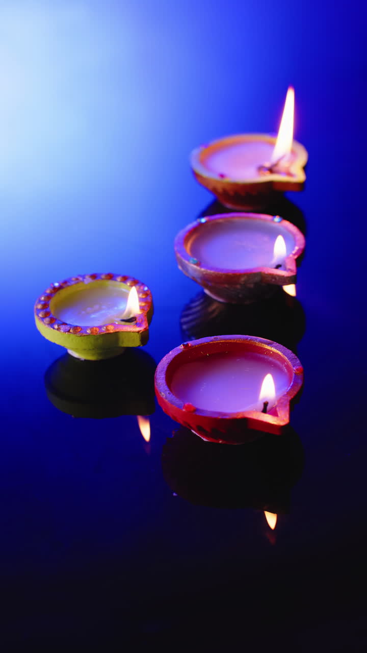 Vertical video of burning candles celebrating diwali on blue background, with copy space