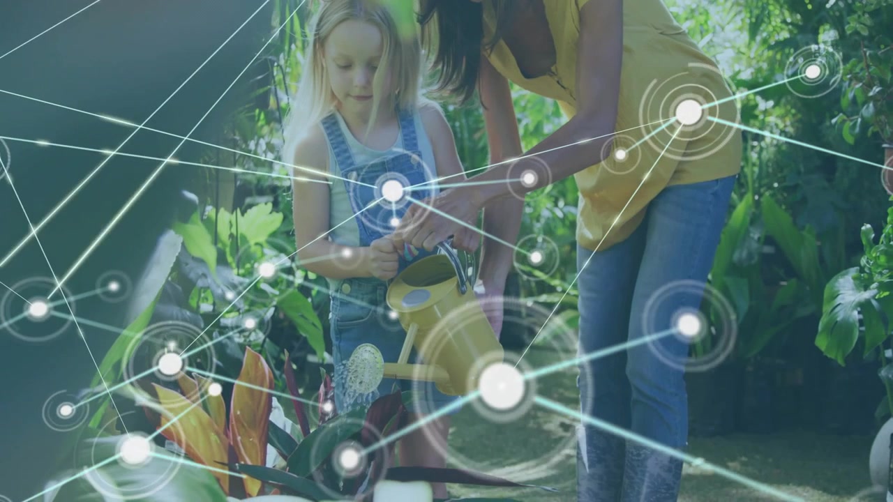 Caregiver guiding child's hands in greenhouse, child tipping yellow watering can, nodes expanding