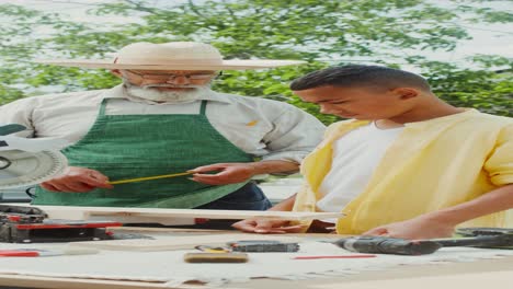 senior craftsman teaching teenager woodworking