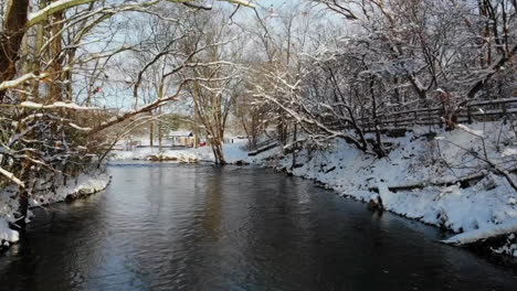 Toma-Aérea-De-Un-Arroyo-En-Un-Bosque-Cubierto-De-Espectáculos-En-Michigan,-Estados-Unidos