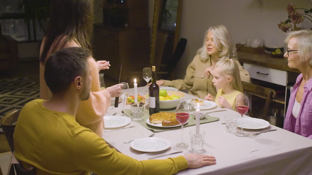 mujer sirviendo pastel a su familia durante una cena en casa 1