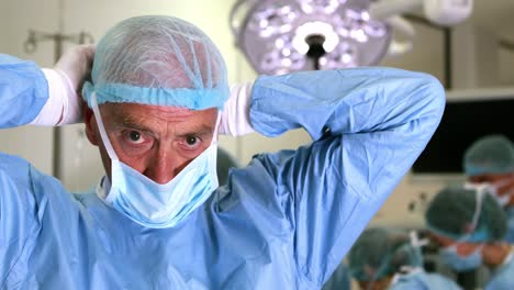 medical professor in surgical gear putting on mask