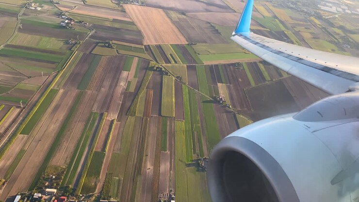 Close-up opname van vliegtuigturbine en landelijke kleurrijke landbouwvelden met verschillende patronen tijdens de landingsnadering