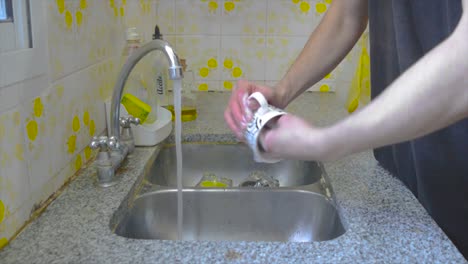 male person washing a coffee mug at home