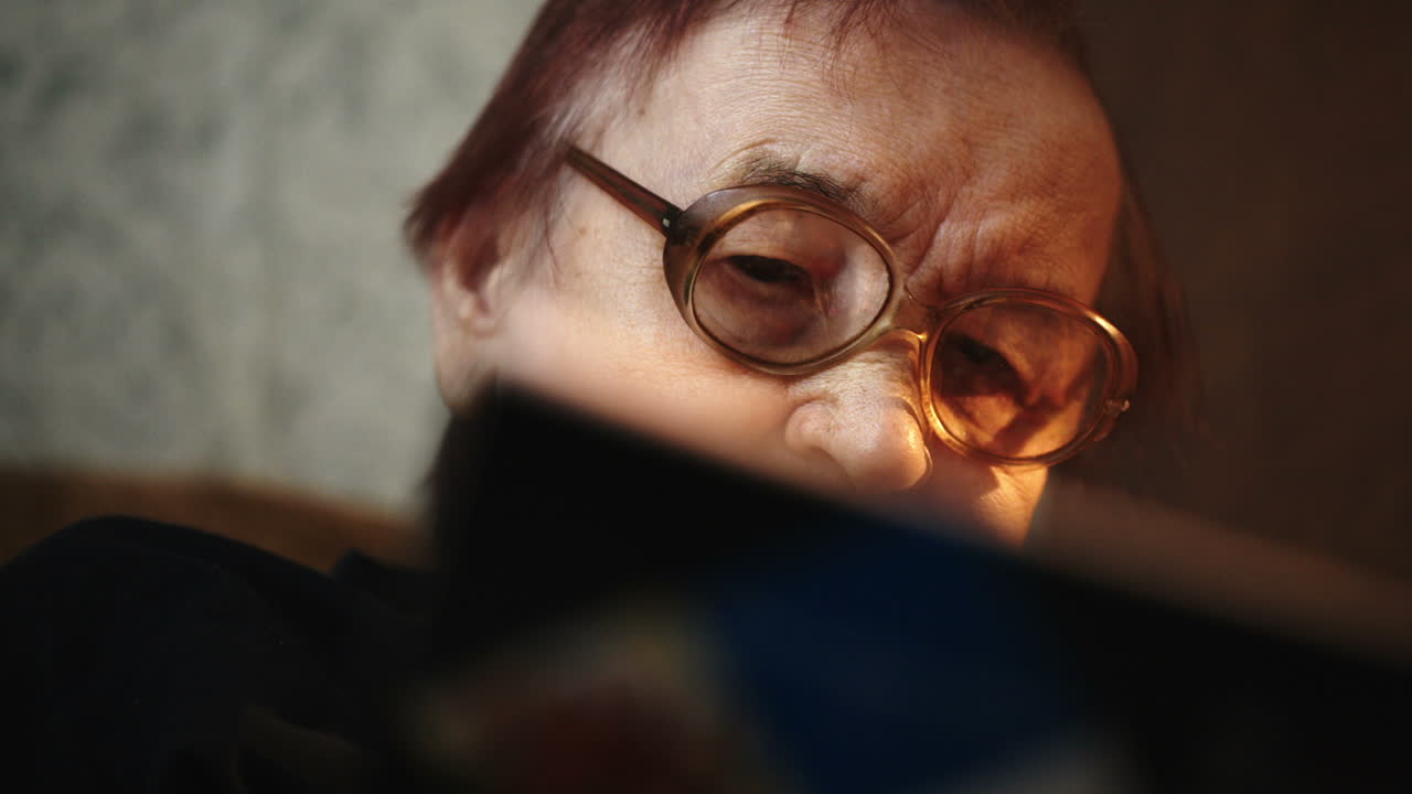 mujer mayor con gafas y libro en casa