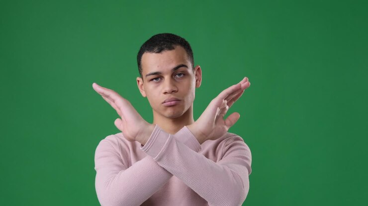 Man crossing arms gesturing no over green background