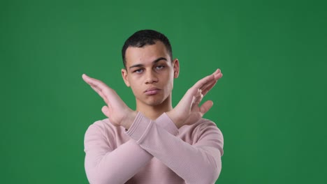 man crossing arms gesturing no over green background