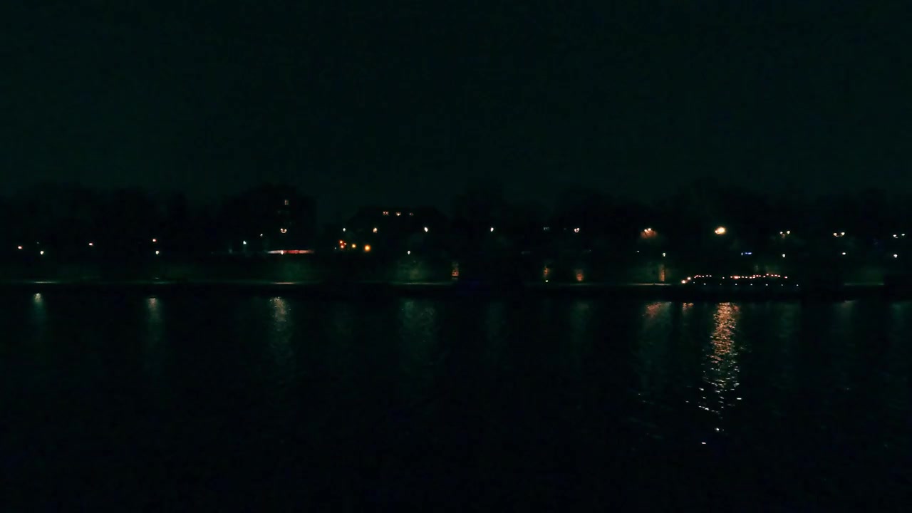 近くの建物や街灯の明かりが、川沿いの都市公園の水面を照らしています。 shore沿いの数隻のボートが、静かな雰囲気を醸し出しています。