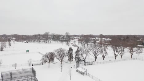 aerial, empty neighborhood community park sports complex covered in snow during winter