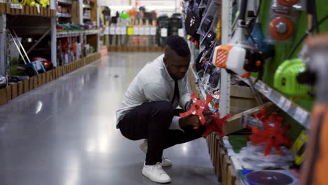 Young-guy-inspects-goods-on-the-shelf-of-a-hardware-store