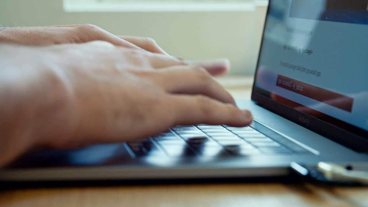 manos del hombre escribiendo en un teclado de computadora portátil