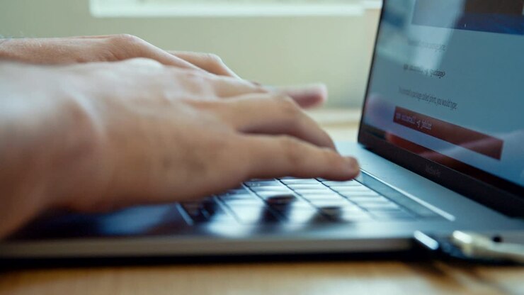 Mani di un uomo che digitano sulla tastiera di un computer portatile.