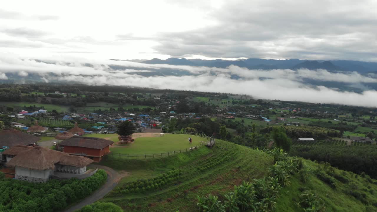 retirar la revelación de una pareja parada en la cima de una colina en el asia rural viendo el amanecer mientras la nube baja y espesa se despeja para el día sobre los campos