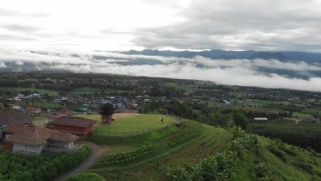 Retirar-La-Revelación-De-Una-Pareja-Parada-En-La-Cima-De-Una-Colina-En-El-Asia-Rural-Viendo-El-Amanecer-Mientras-La-Nube-Baja-Y-Espesa-Se-Despeja-Para-El-Día-Sobre-Los-Campos