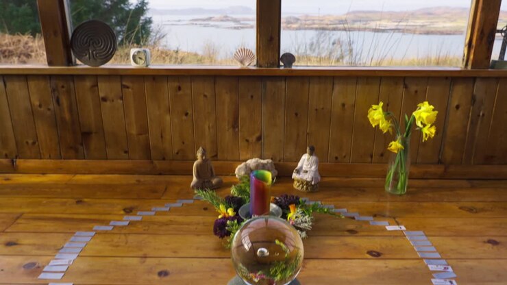 Sala del tempio spirituale con cristalli, sfere e statue di Buddha, l'inquadratura verso l'alto rivela una meditazione con vista sulla natura.