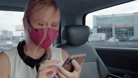 mujer pasajera en taxi usando máscara y usando teléfono