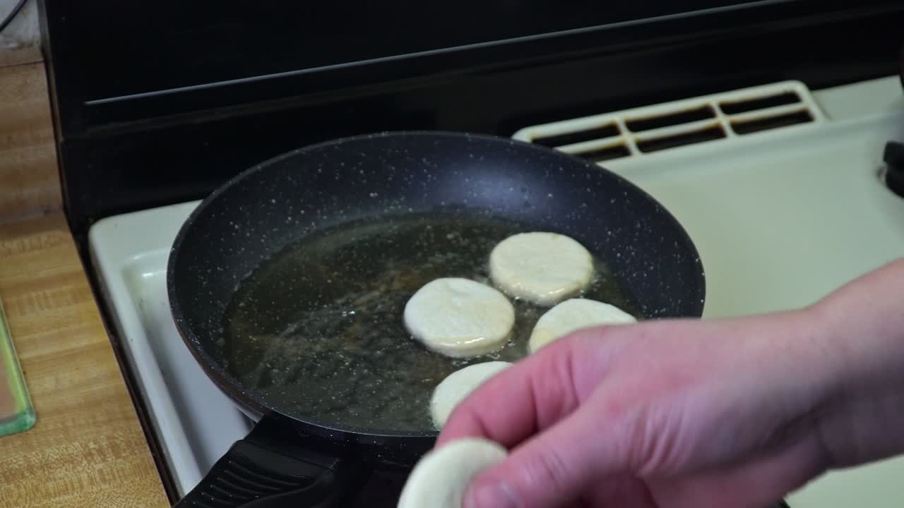 여자가 뜨거운 기름에 생 도을 넣습니다.