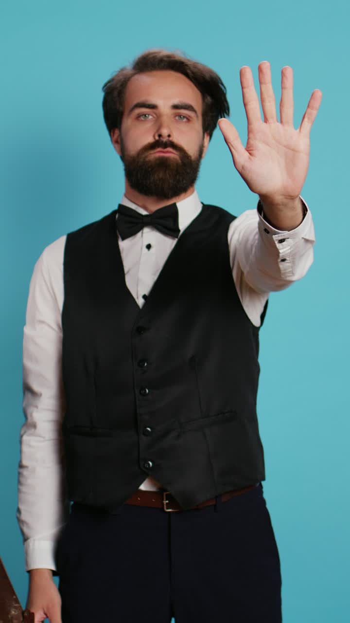 Vertical video Bellboy raises hand to show stop sign