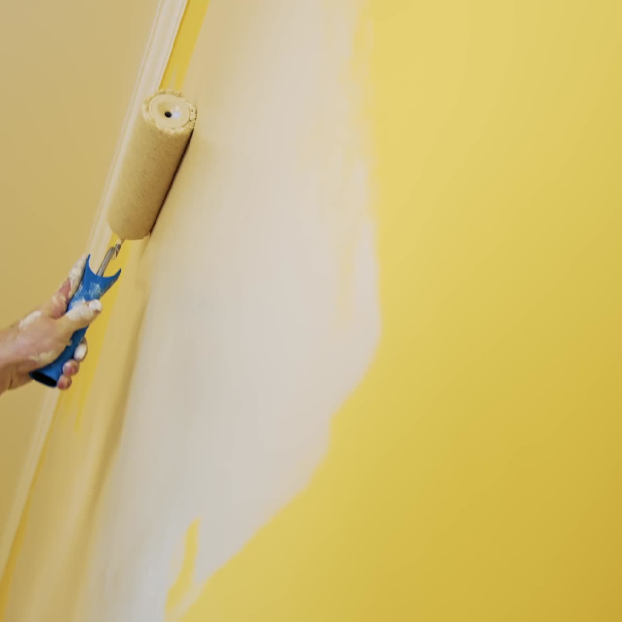 Man painting wall in room. Close up of man in new apartment renovating room painting wall with brush roller