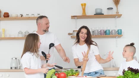 positive mom dad and two children in white tshirts are dancing in the kitchen while cooking positive mom dad and two children in white tshirts are dancing in the kitchen while cooking happy family together