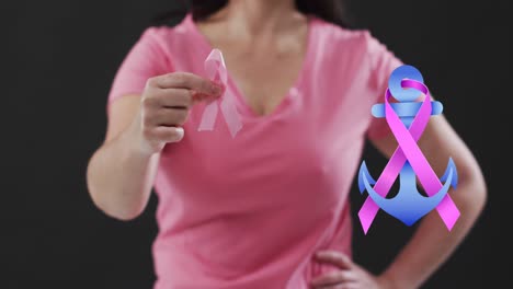 Ribbon-over-a-anchor-icon-over-mid-section-of-woman-holding-a-pink-ribbon-against-black-background