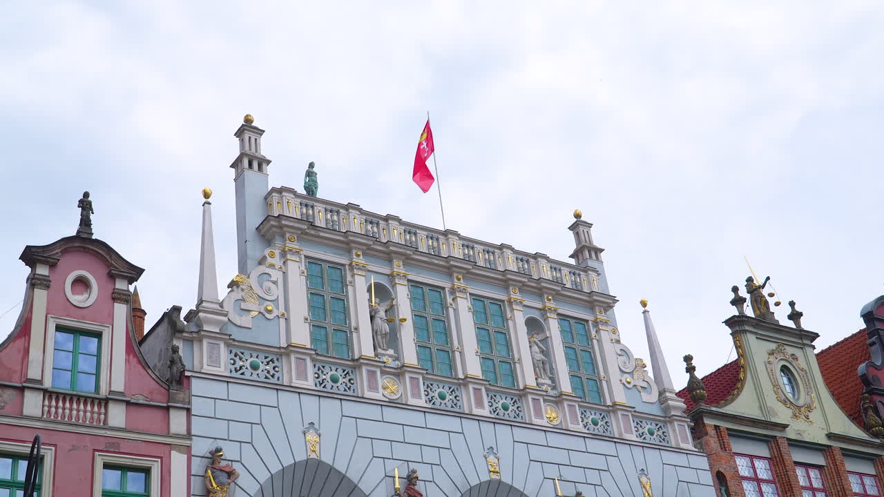 Detailed view of Gdansk’s Artus Court facade with red flag and historical statues