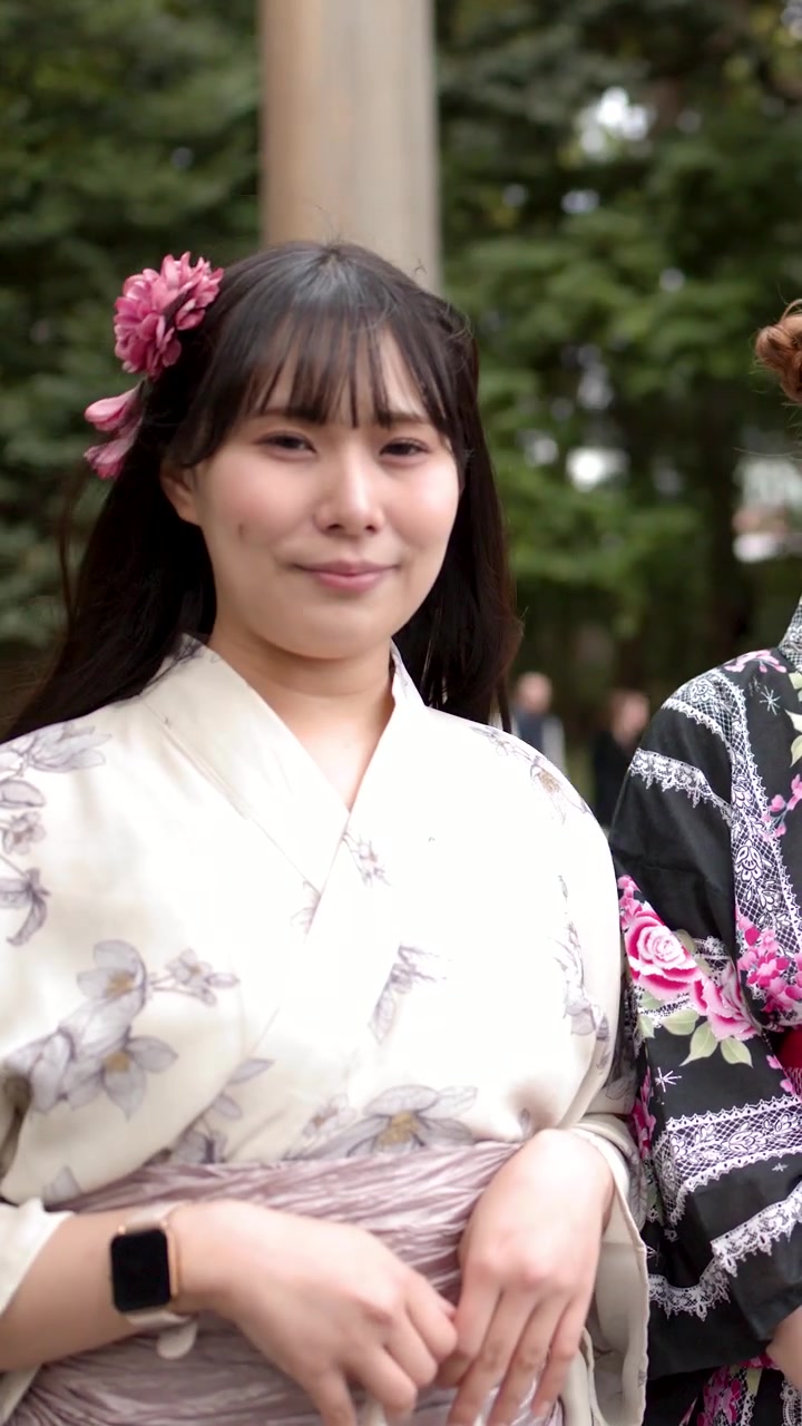 柔らかな自然光と木々を背景に、花柄の着物を着た日本人女性が屋外でポーズをとる。