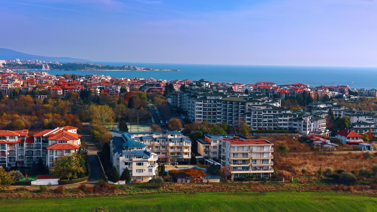 Kıyıya yakın konut apartman komplekslerinin havadan görünümü. Kırmızı çatılı, ağaçlı ve uzakta deniz manzaralı modern çok katlı binaların orta mesafeli havadan çekimi.
