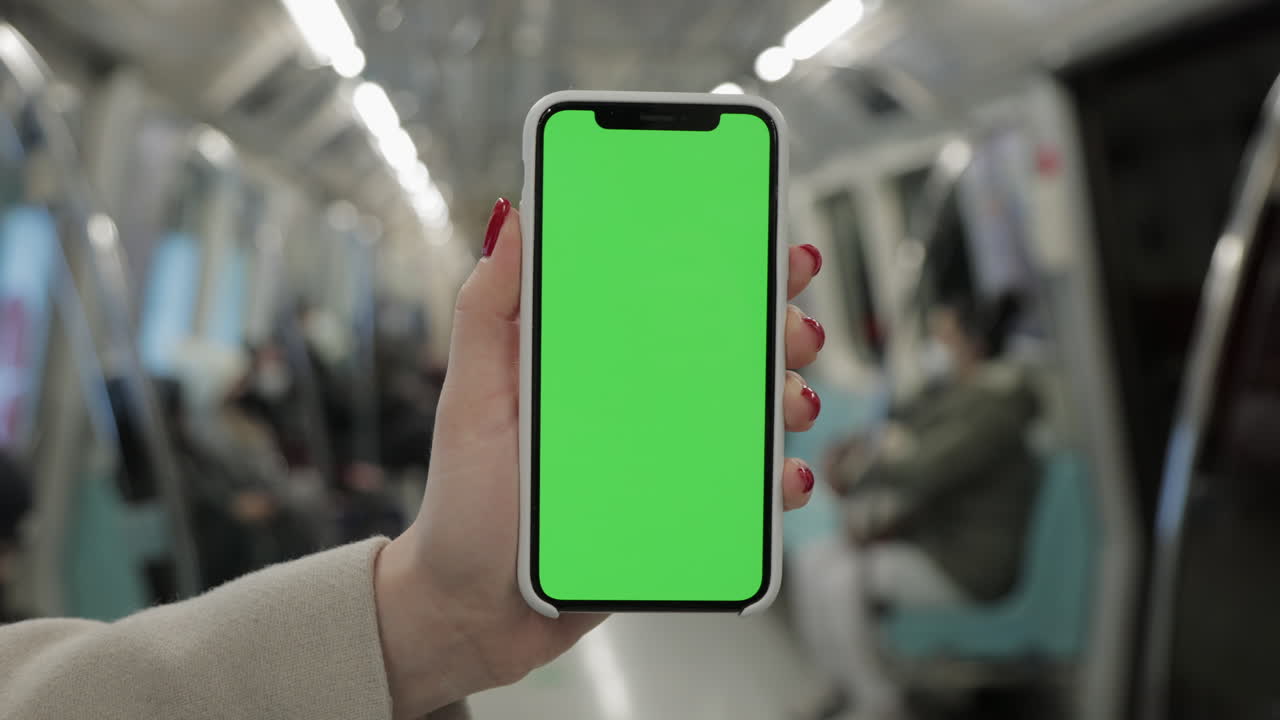 Donna con uno smartphone con schermo verde in metropolitana