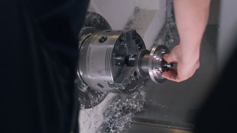 male technician measures cinema lens workpiece on lathe