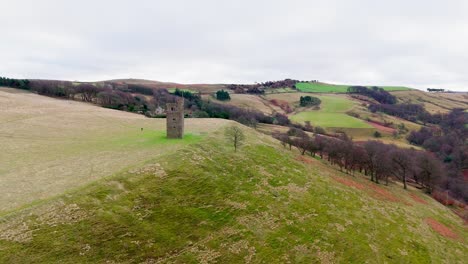 Old-derelict-castle,-monument,-disused-stone-tower,-with-people-walking-around-and-flying-a-drone