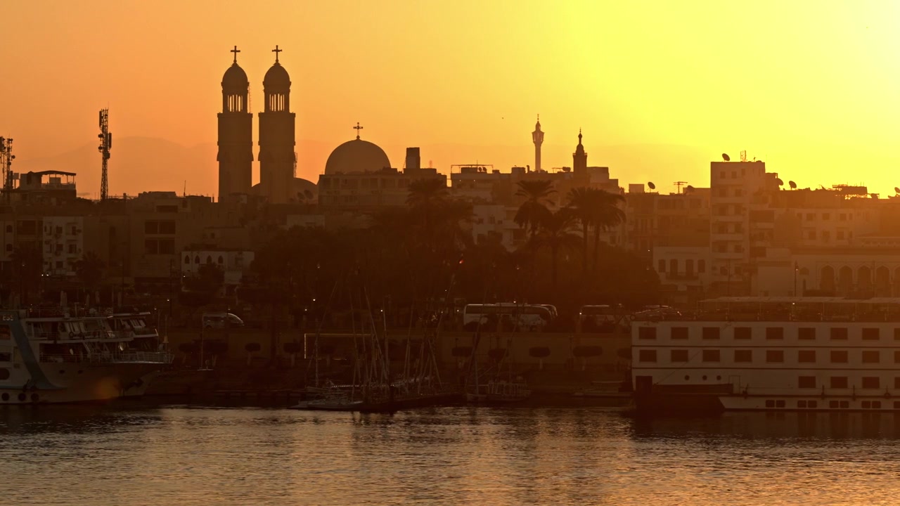 Una silhouette dello skyline della città di Luxor è catturata durante un vibrante tramonto dorato sul fiume Nilo