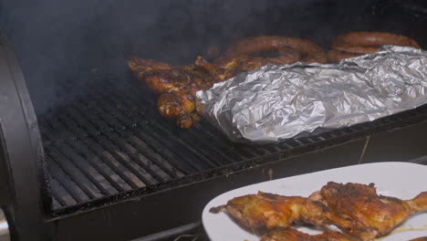 man with plate takes bbq chicken thighs off of smoking bbq pit