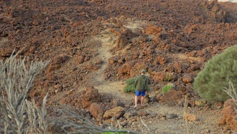 Male-tourist-descents-playful-in-rugged-volcanic-landscape,-Tenerife