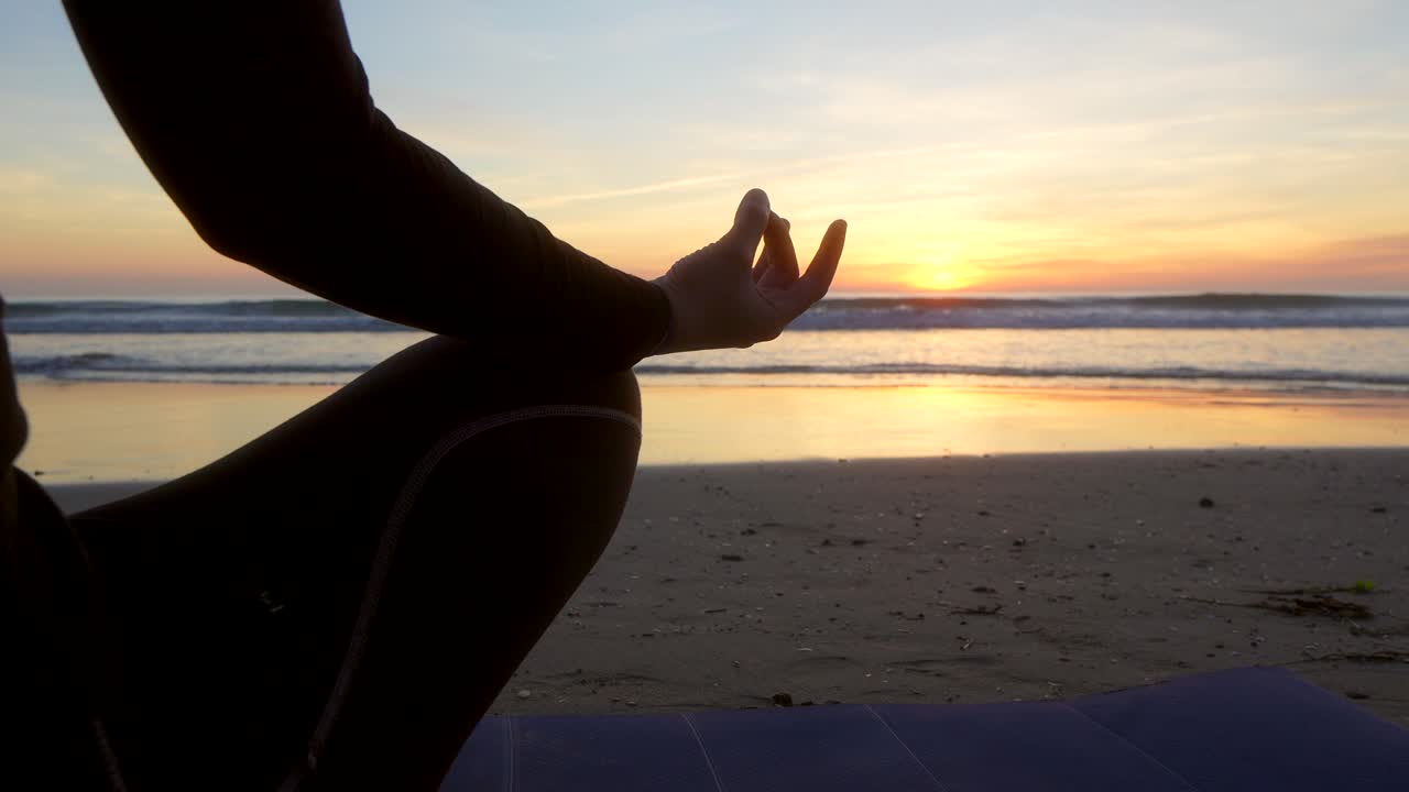 mantra con la mano de una mujer que está haciendo yoga frente al mar