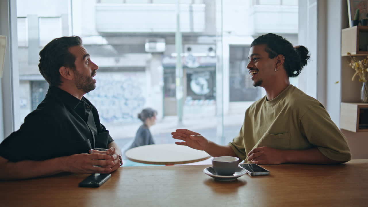 Male best friends talking in cafeteria at weekend closeup. Guys friendly meeting