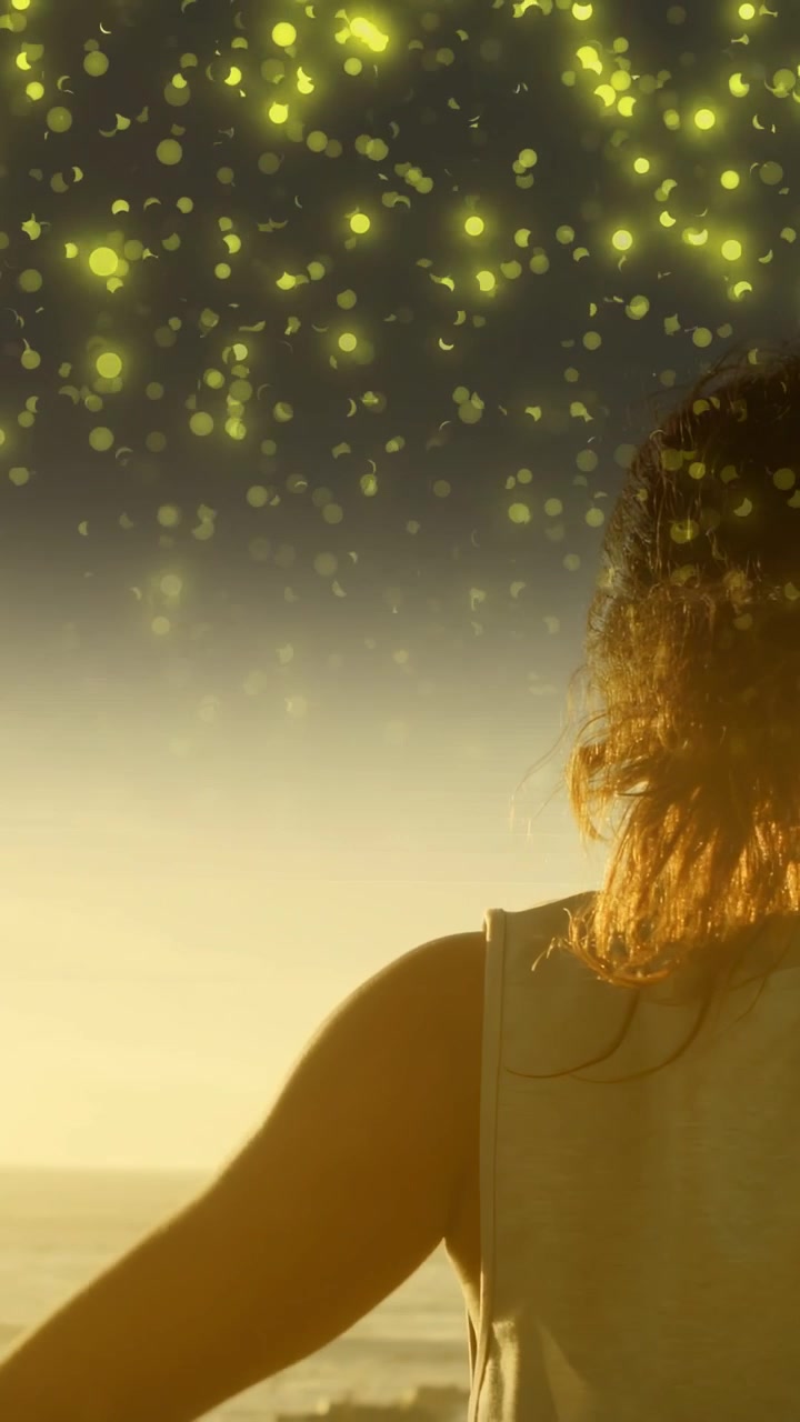 Video vertical: Mujer levantando el brazo en forma de arco con luces del mar flotando por encima, iluminando su cabello por salud.