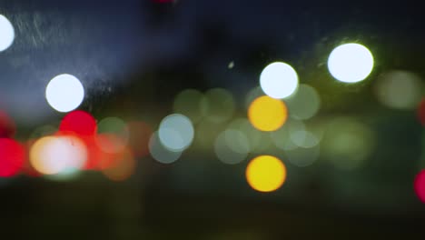 luces de la ciudad fuera de foco en la noche desde el interior de un coche en movimiento