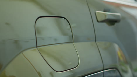 close up of driver opening ev car charging port flap to charge battery