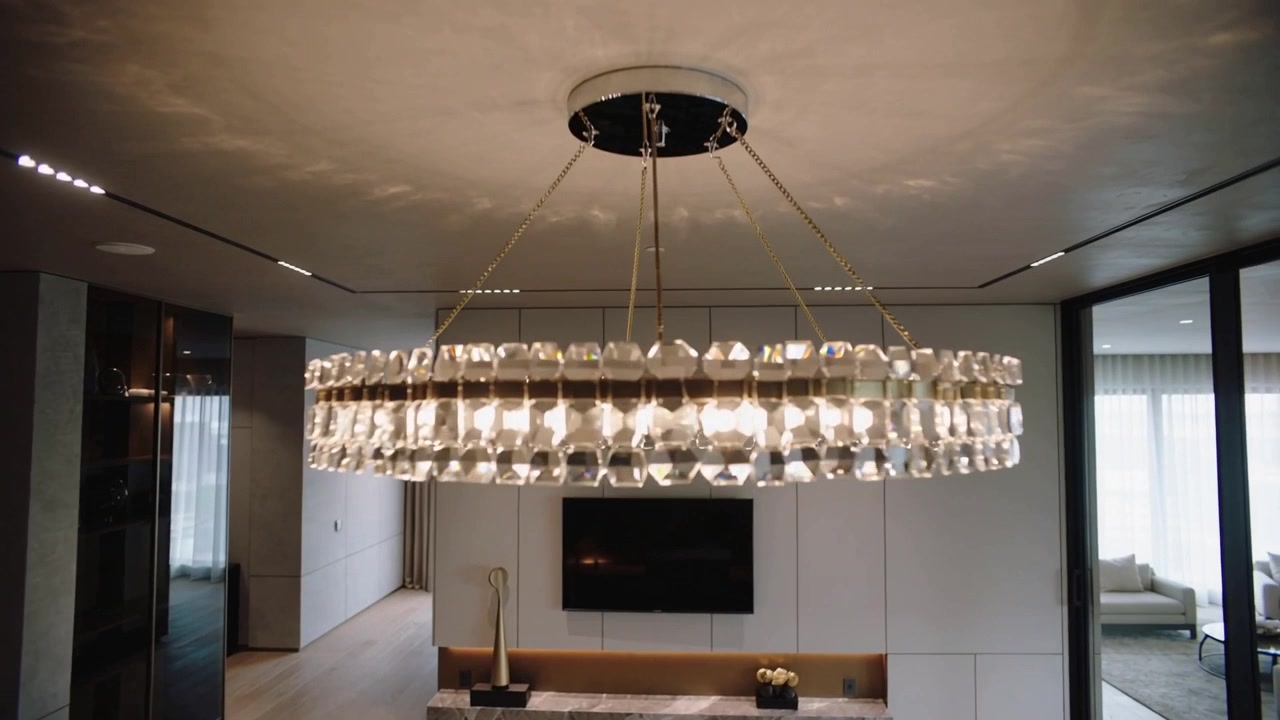 Panning camera centering large crystal chandelier above marble unit in living room revealing facets
