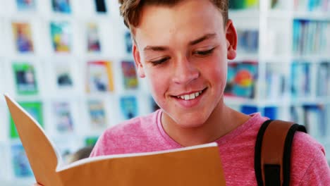 un escolar sonriente leyendo un libro en la biblioteca