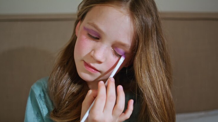 Cute child using makeup in mothers room closeup. Little kid putting eyeshadows