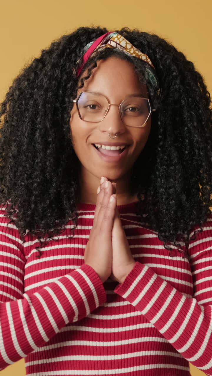 Young Woman with Curly Hair Smiling and Making Namaste Gesture