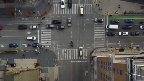 Antena-Recortada-De-Arriba-Hacia-Abajo-Tráfico-De-Intersección-De-Calles-De-La-Ciudad-Ocupada-Con-Peatones-Y-Bicicletas