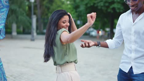 joyful group of friends dancing outdoors in a park