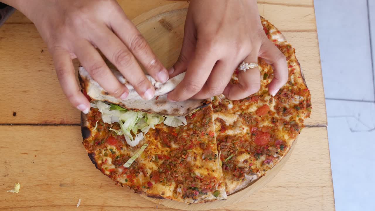 Mani che arrotolano il tradizionale Lahmacun turco con lattuga fresca