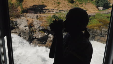 silueta de una mujer bebiendo una bebida caliente en un café junto a la ventana en las montañas de fondo y un