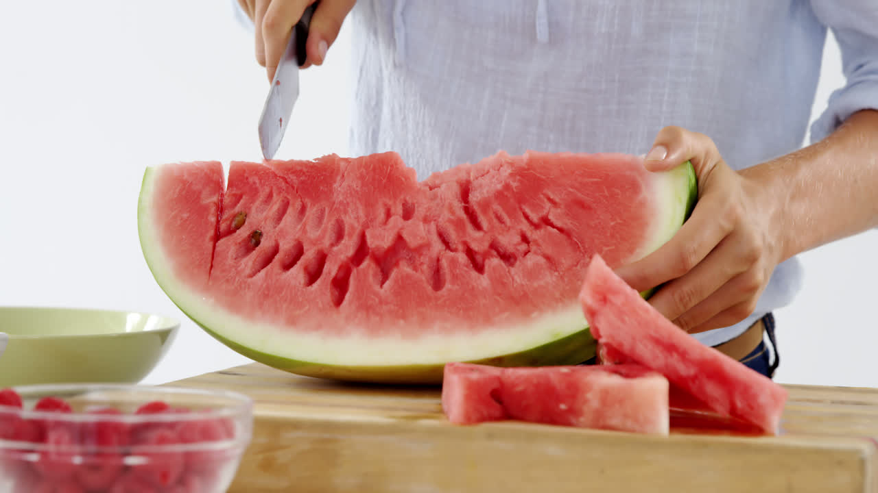 mujer cortando frutas en la tabla de cortar contra un fondo blanco
