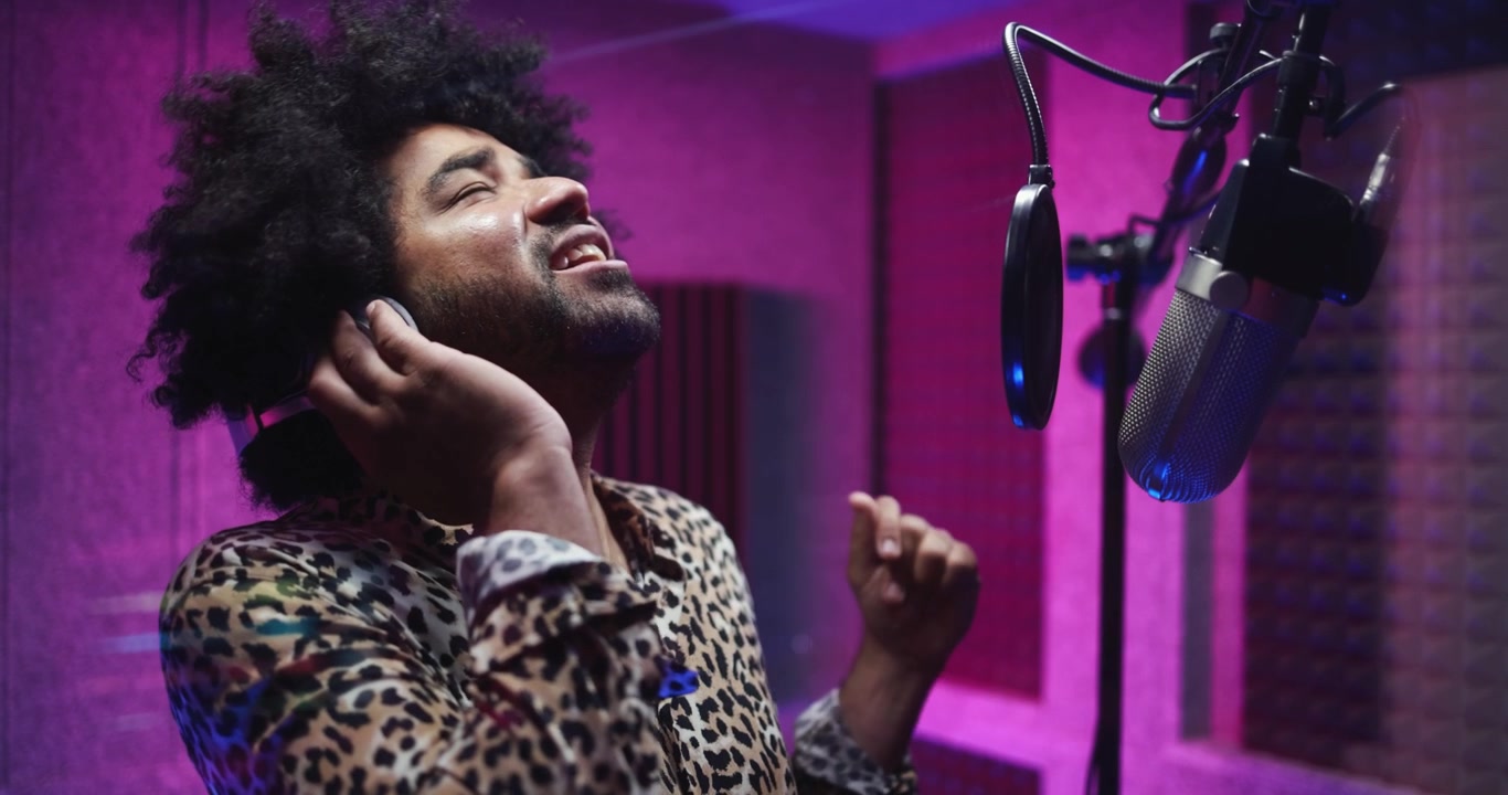 Passionate Male Singer Recording Vocals in a Vibrant Music Studio